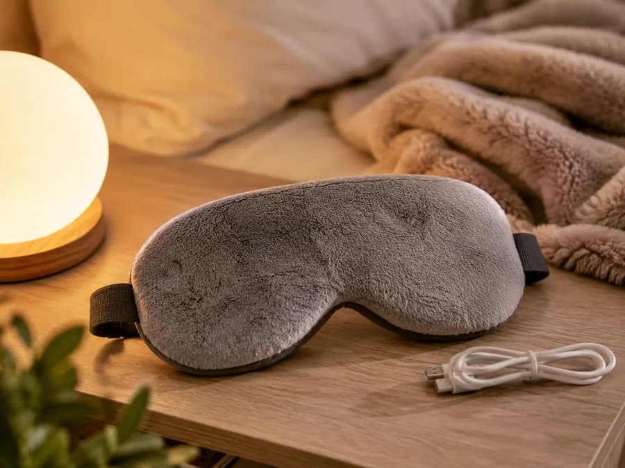 Heated eye mask on bedside table with warm sleep routine setting