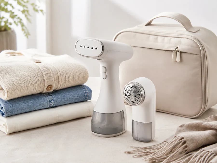 Mini garment steamer and lint remover with folded clothes and travel bag